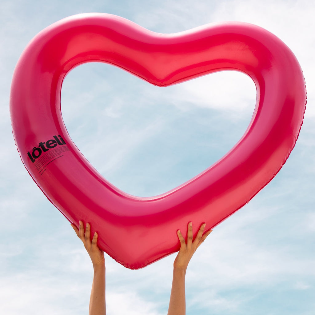 Woman holding metallic pink heart float up to the sky with logo facing camera