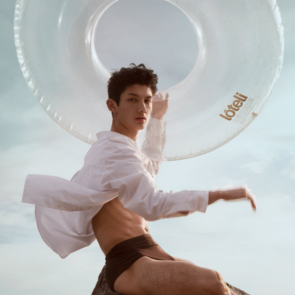 Swim ring pool float held in the air with young man wearing white shirt blown by the wind